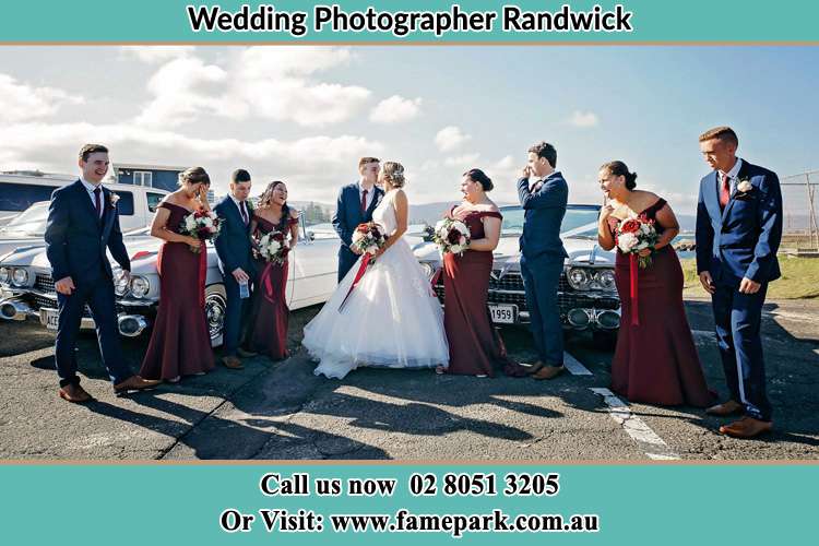 Photo of the Groom and the Bride kissing with the secondary sponsors at the parking lot Randwick NSW 2031